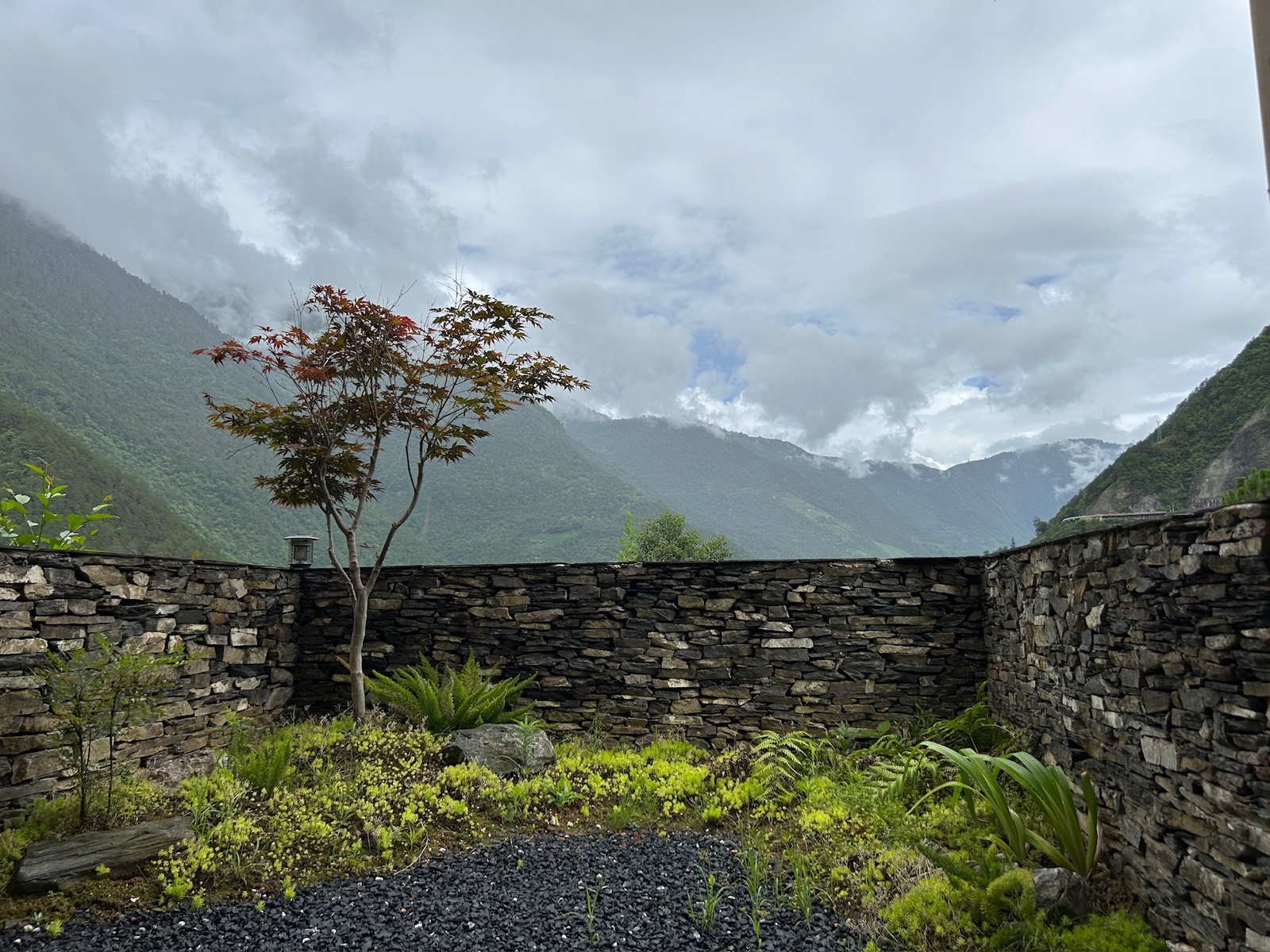 Stone wall and mountain valley under heavy clouds